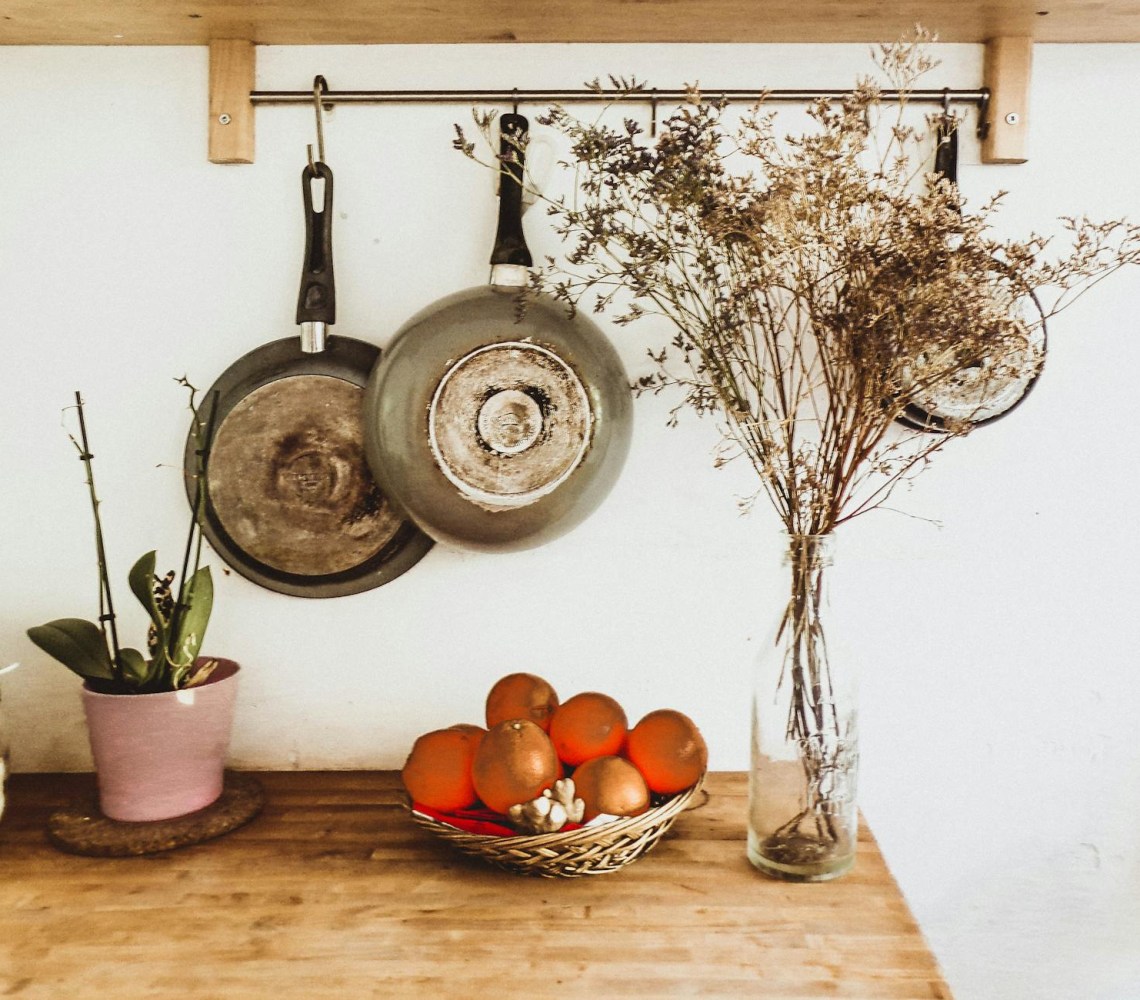 two gray frying pans hanging on wall