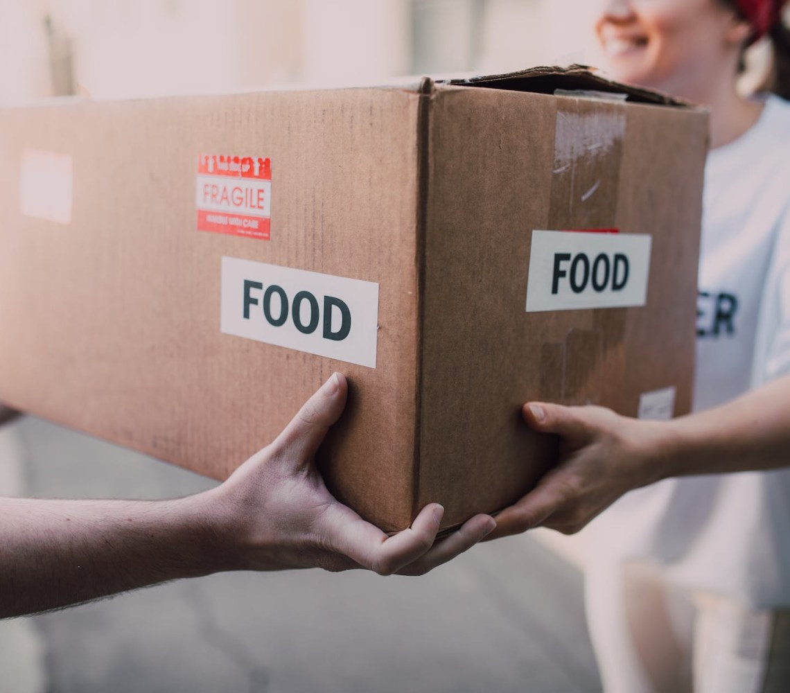 people handing over a brown box